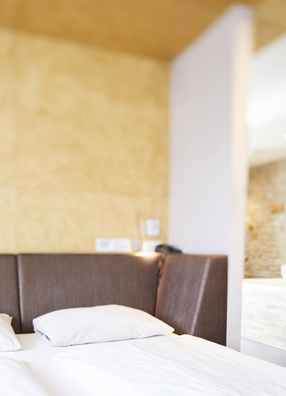 Blick auf das Bett in der Luxus Spa Suite Blattgold im Hotel Guglwald. Im Bild rechts ist die Whirlwanne im Zimmer zu sehen.