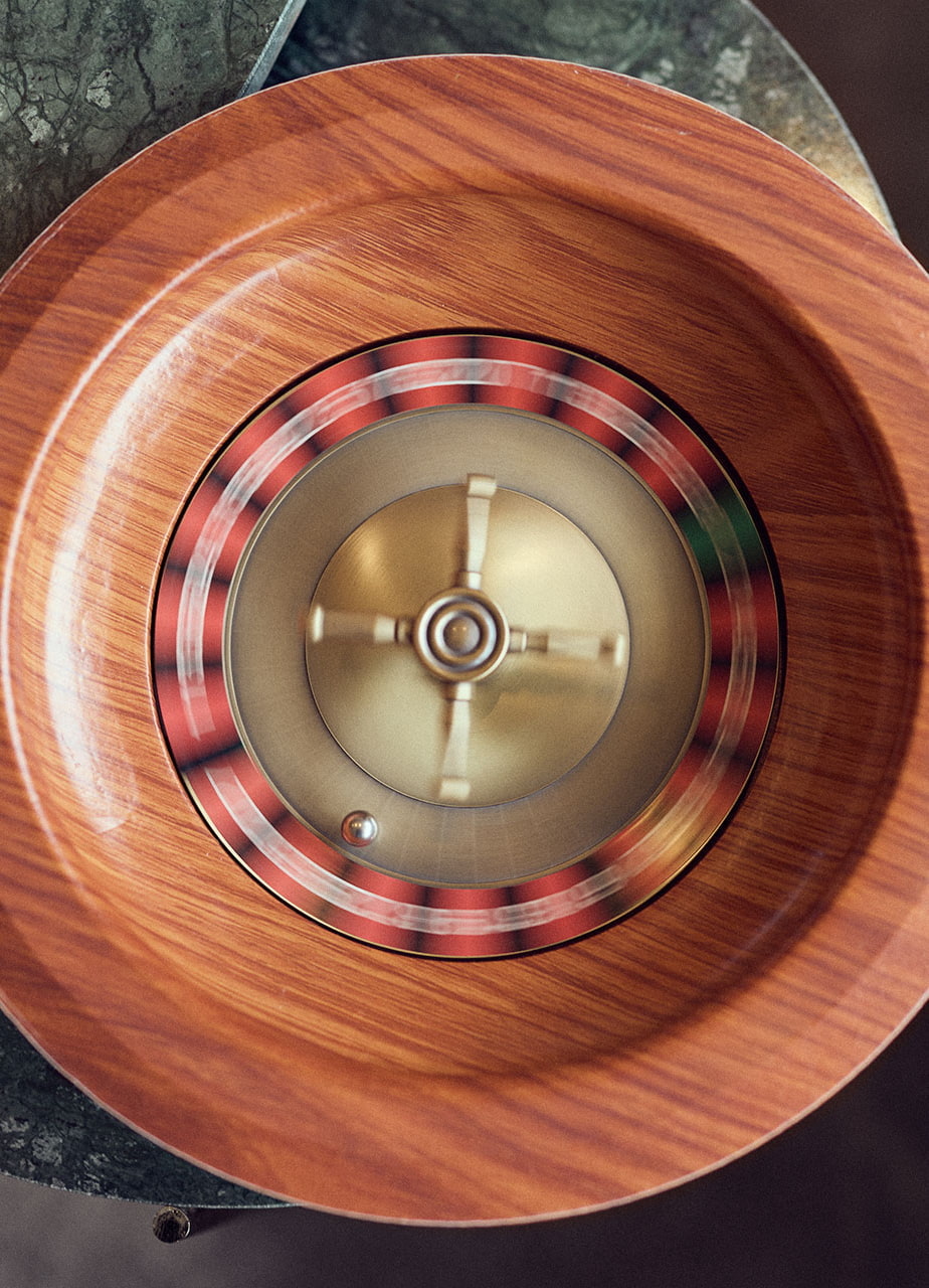 Ein Roulette-Spiel, dessen Kurbel und Kugel sich drehen auf einem Beistelltisch in Marmoroptik.